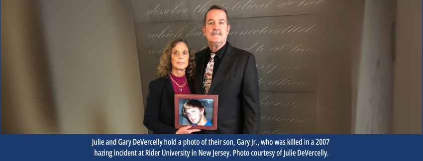 A man and woman stand holding a portrait of their son.